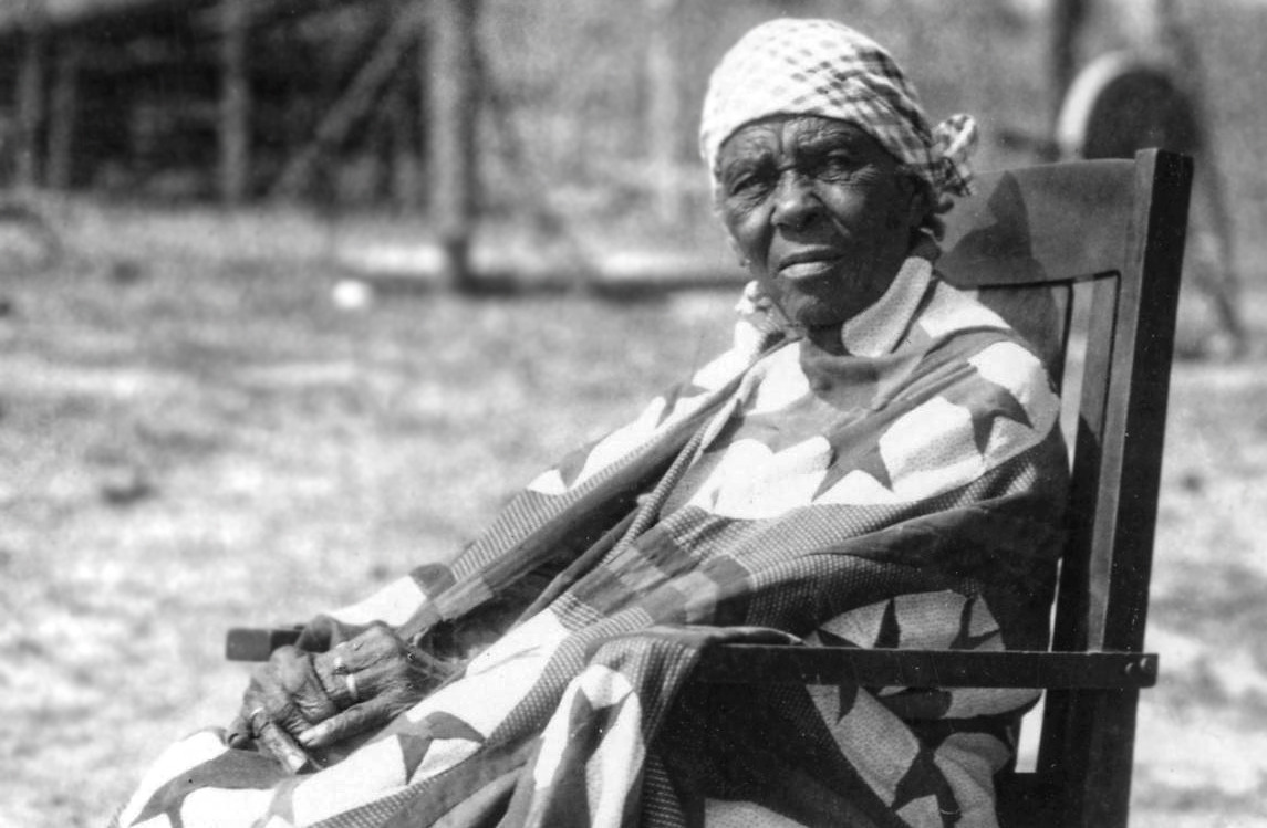 An elderly Freedman woman sits outdoors in a rocking chair