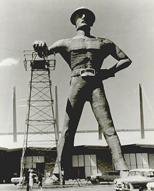 Historic photograph of the Golden Driller statue with cars and people visible